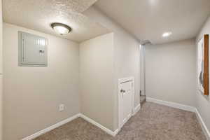 Hallway with carpet flooring, electric panel, a textured ceiling, and recessed lighting