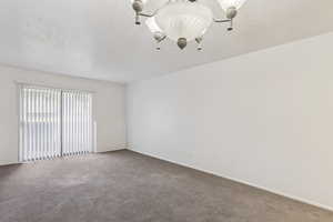 Carpeted empty room with a textured ceiling and baseboards