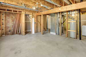 Unfinished basement with washer / dryer, water heater, and heating unit