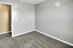 Spare room with dark colored carpet and baseboards