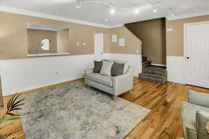 Living area with ornamental molding, stairs, and wood finished floors