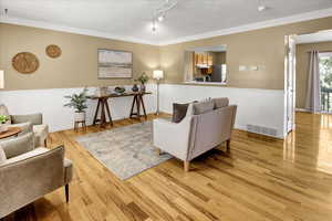 Living area with crown molding and light wood-style floors
