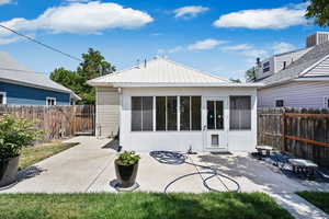 Back of property featuring a fenced backyard, a patio, and a metal roof