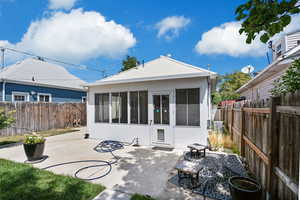 Back of house featuring a sunroom, a patio area, a fenced backyard, and stucco siding