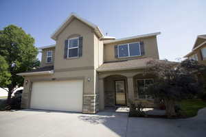 View of front of home featuring concrete driveway, an attached garage, stucco siding, and stone siding