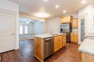 Kitchen featuring appliances with stainless steel finishes, light brown cabinets, a chandelier, light stone countertops, and recessed lighting
