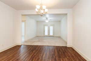 Spare room featuring a chandelier, dark wood-style floors, and ceiling fan