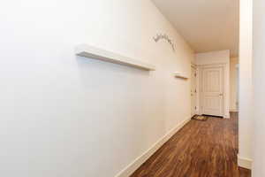 Corridor with dark wood-type flooring and baseboards