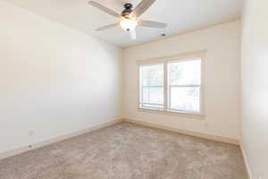 Empty room featuring light carpet and a ceiling fan