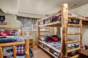 Bedroom with a textured ceiling, and carpet flooring