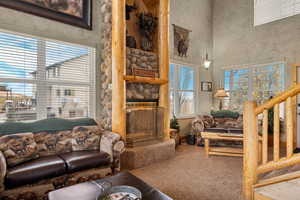 Living area featuring a fireplace, carpet flooring, and a towering ceiling