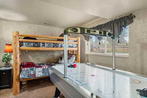Carpeted bedroom with wallpapered walls and a textured ceiling