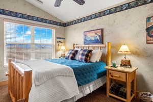 Bedroom with vaulted ceiling, a ceiling fan, and carpet floors