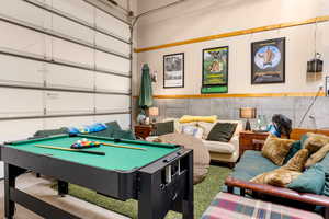 Rec room featuring a garage, pool table, and wainscoting