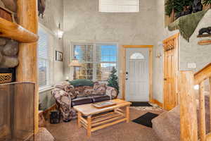 Carpeted foyer entrance featuring a towering ceiling and stairway