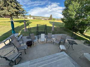 View of patio featuring an outdoor fire pit, bordering a golf course