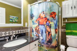 Bathroom with a shower stall, vanity, tile walls, and crown molding