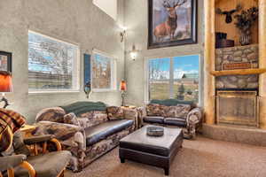 Living area featuring a towering ceiling, a fireplace, and carpet floors