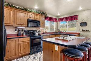 Kitchen with black appliances, dark countertops, a kitchen island, and a kitchen bar