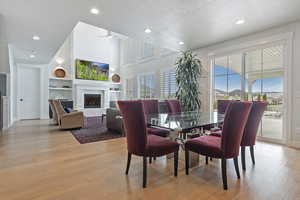 Dining space featuring light wood-style floors, a fireplace, recessed lighting, a textured ceiling, and a ceiling fan