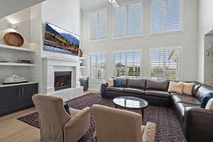 Living room with light wood finished floors, a fireplace, and a ceiling fan
