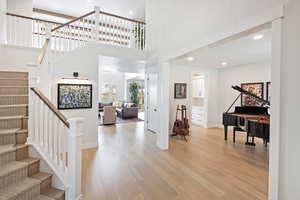 Foyer with light wood finished floors, recessed lighting, stairway, and a high ceiling