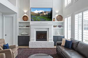 Living area with a brick fireplace, a high ceiling, and wood finished floors
