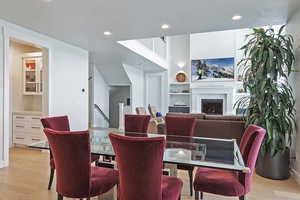 Dining room with light wood finished floors, built in shelves, a textured ceiling, a fireplace, and recessed lighting
