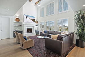 Living room featuring a textured ceiling, recessed lighting, built in features, wood finished floors, and a fireplace