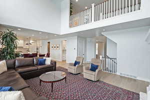 Living area featuring light wood-type flooring, recessed lighting, and a high ceiling