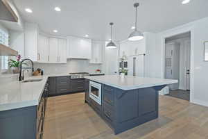 Kitchen featuring light wood-style flooring, light countertops, white cabinetry, recessed lighting, and a kitchen island