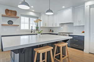 Kitchen with white cabinets, light wood-type flooring, a breakfast bar, a kitchen island, and recessed lighting