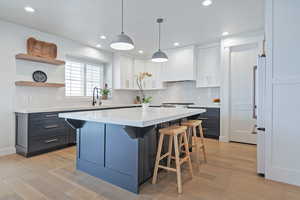Kitchen featuring white cabinetry, a breakfast bar area, light countertops, a center island, and recessed lighting