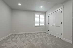 Unfurnished bedroom featuring carpet flooring, a textured ceiling, recessed lighting, and a closet