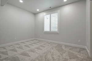 Empty room with carpet, recessed lighting, and a textured ceiling