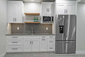 Kitchen featuring appliances with stainless steel finishes, white cabinets, dark countertops, and open shelves