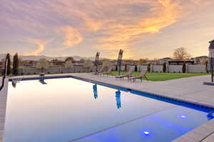 Pool at dusk with a patio area, a mountain view, and a diving board