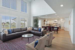 Living area featuring recessed lighting, light wood finished floors, a textured ceiling, and a towering ceiling