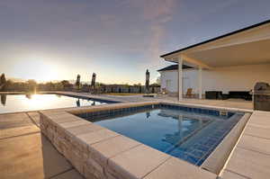 Pool at dusk featuring a patio area and an outdoor pool
