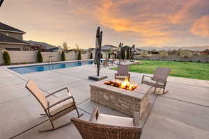 View of pool featuring an outdoor fire pit, a patio area, a fenced backyard, and a mountain view