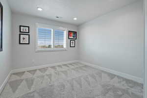 Unfurnished room featuring light carpet, a textured ceiling, and recessed lighting