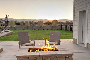 Fenced backyard featuring a fire pit, a mountain view, and a patio