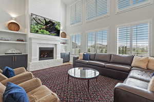 Living room featuring a brick fireplace, a towering ceiling, and built in features