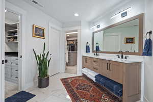 Full bathroom with double vanity, a walk in closet, marble finish floors, and recessed lighting