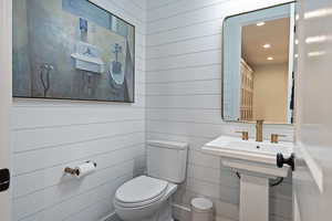 Half bathroom featuring wooden walls and recessed lighting