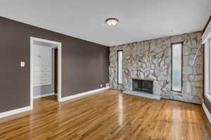 Unfurnished living room featuring hardwood / wood-style floors and a stone fireplace