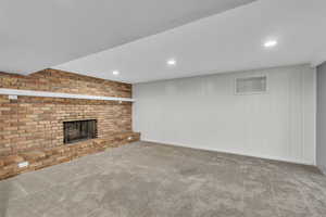 Unfurnished living room with a brick fireplace, carpet flooring, and recessed lighting
