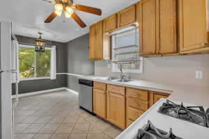 Kitchen featuring freestanding refrigerator, light countertops, dishwasher, ceiling fan, and decorative light fixtures