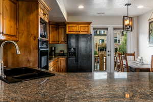 Kitchen featuring black appliances, brown cabinets, a textured ceiling, french doors, and pendant lighting