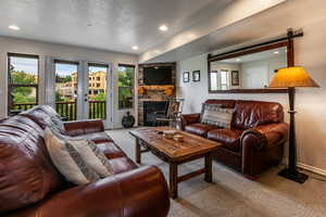 Living room with carpet floors, a barn door, a stone fireplace, a textured ceiling, and recessed lighting